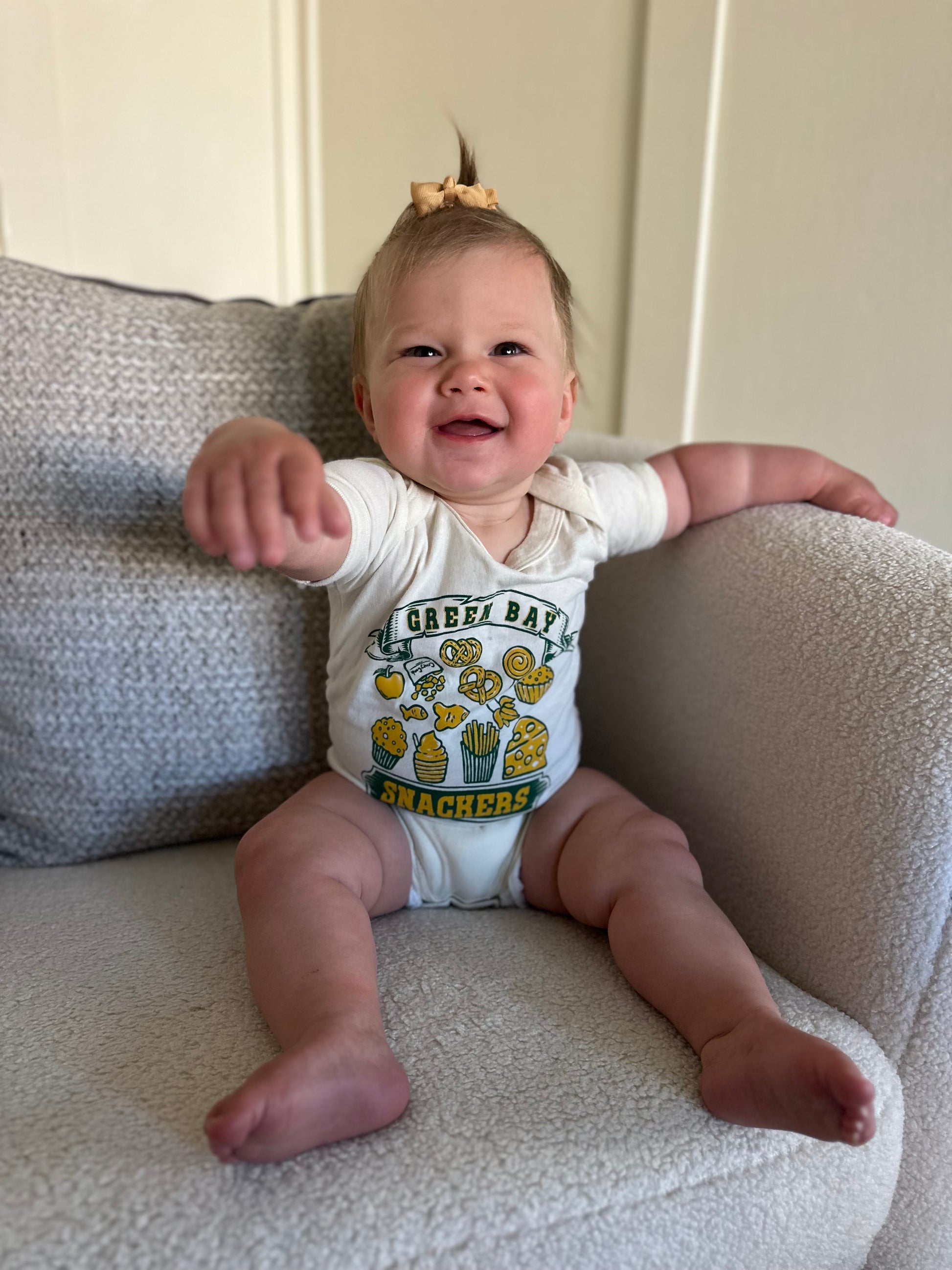 baby smiling wearing a green bay snackers baby onesie